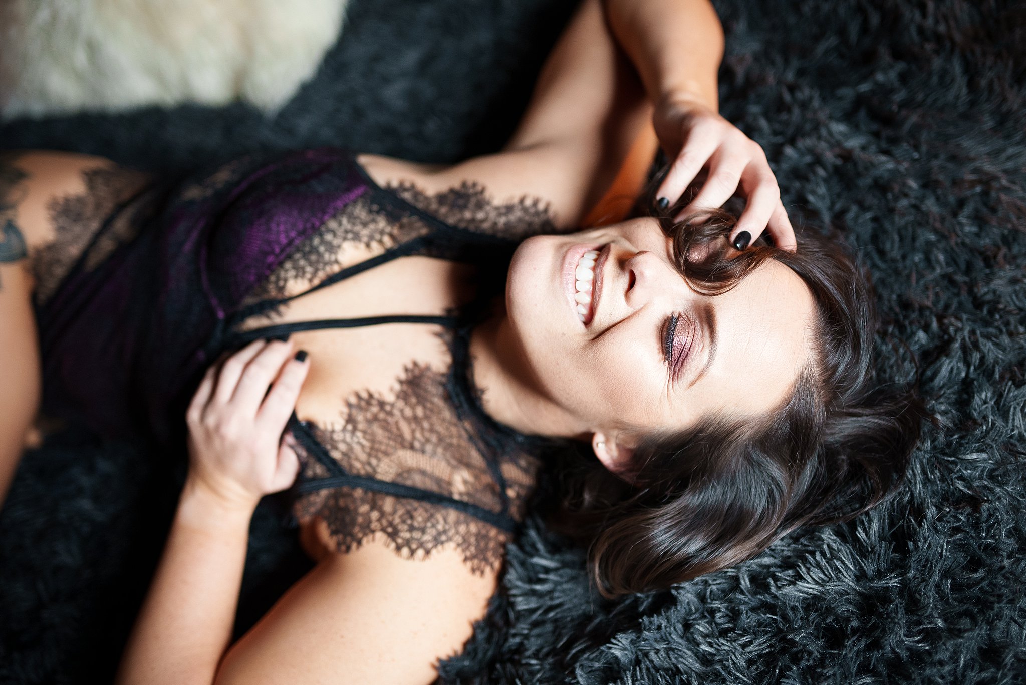 Close up of a brunette wearing lingerie while smiling during her boudoir session. 
